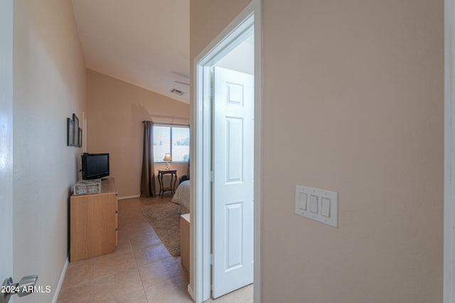 hallway featuring light tile patterned floors and vaulted ceiling