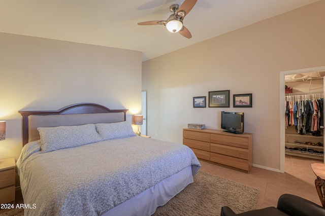 tiled bedroom featuring ceiling fan, vaulted ceiling, a walk in closet, and a closet