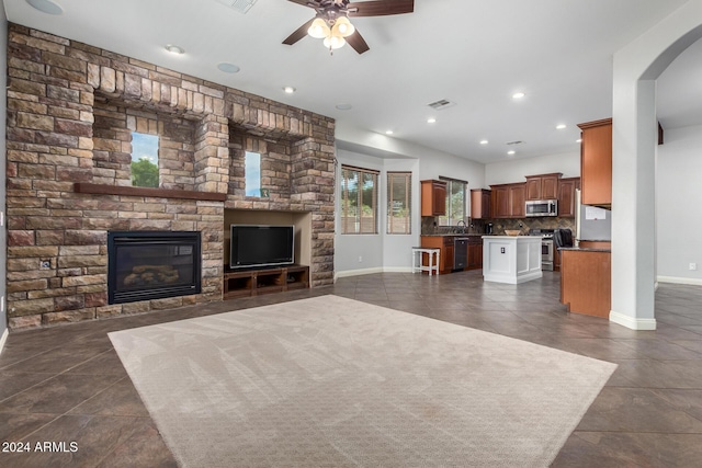 living room featuring ceiling fan, dark tile patterned floors, and a fireplace