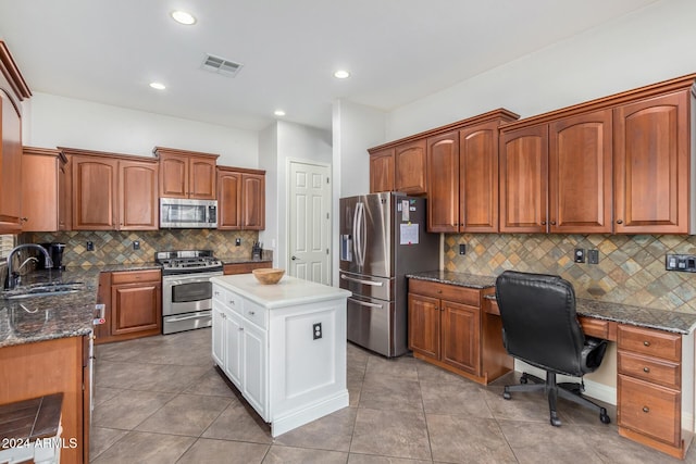 kitchen featuring backsplash, stainless steel appliances, sink, light tile patterned floors, and dark stone countertops