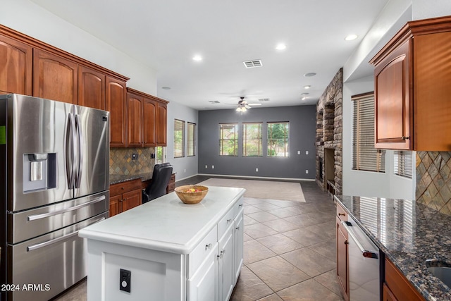 kitchen featuring appliances with stainless steel finishes, tasteful backsplash, dark stone counters, ceiling fan, and light tile patterned floors