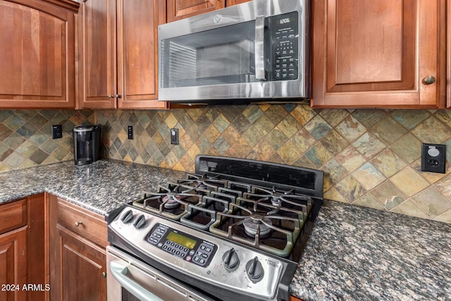 kitchen featuring backsplash, stainless steel appliances, and dark stone counters