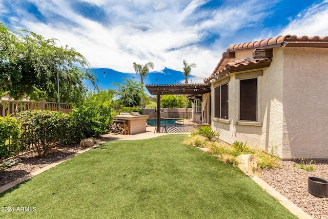 view of yard with exterior kitchen, a patio area, a fenced in pool, and a pergola