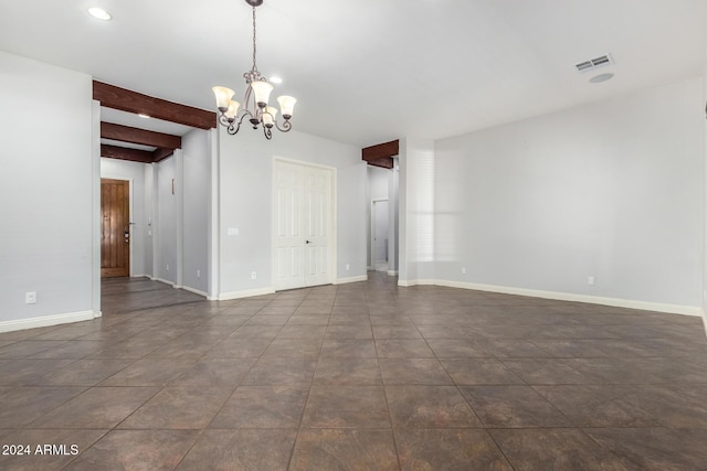 spare room featuring a chandelier and beam ceiling