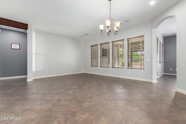 spare room featuring tile patterned flooring and a notable chandelier