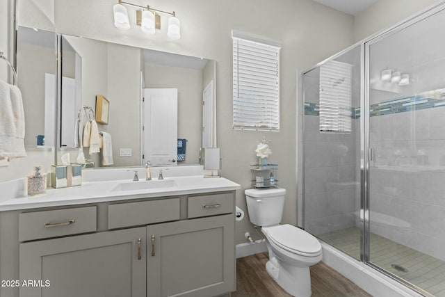 bathroom with a stall shower, vanity, toilet, and wood finished floors