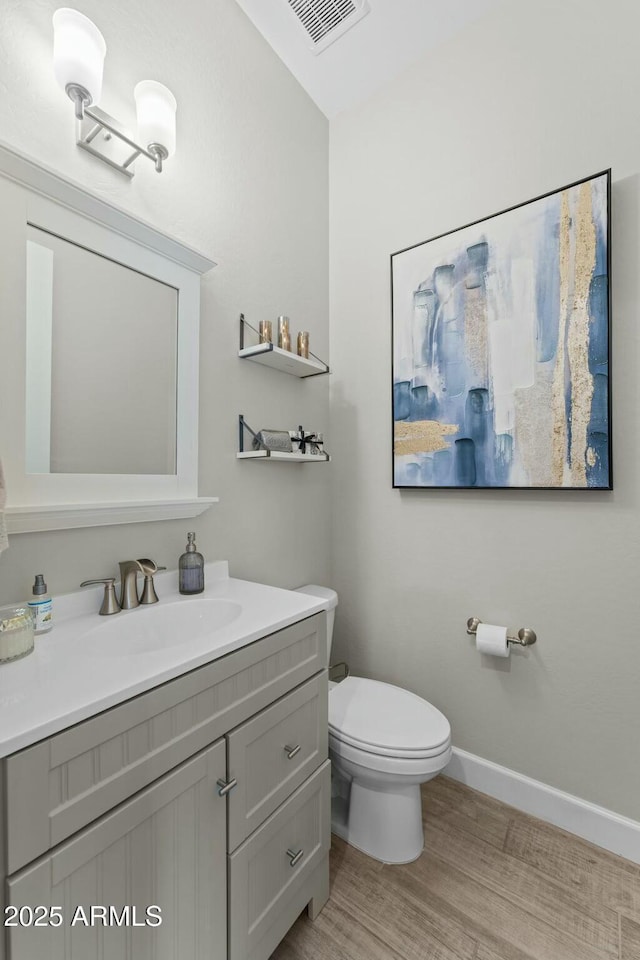 bathroom with baseboards, visible vents, toilet, wood finished floors, and vanity