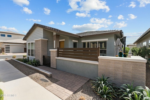 view of front of home with a tiled roof, a fenced front yard, and stucco siding