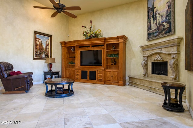 living room featuring ceiling fan, a high ceiling, and a high end fireplace