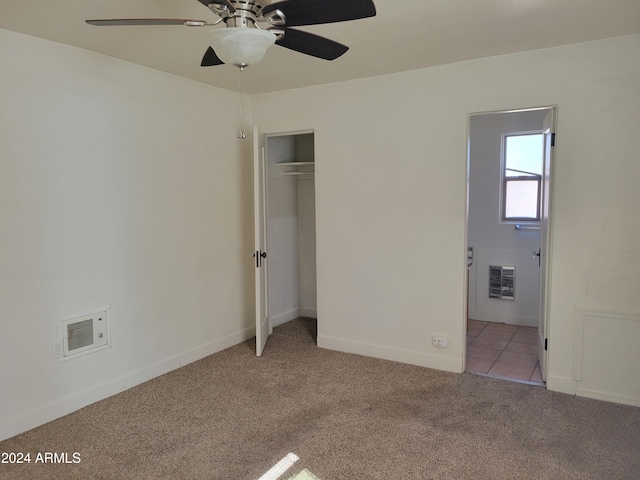 unfurnished bedroom with a closet, light colored carpet, and ceiling fan