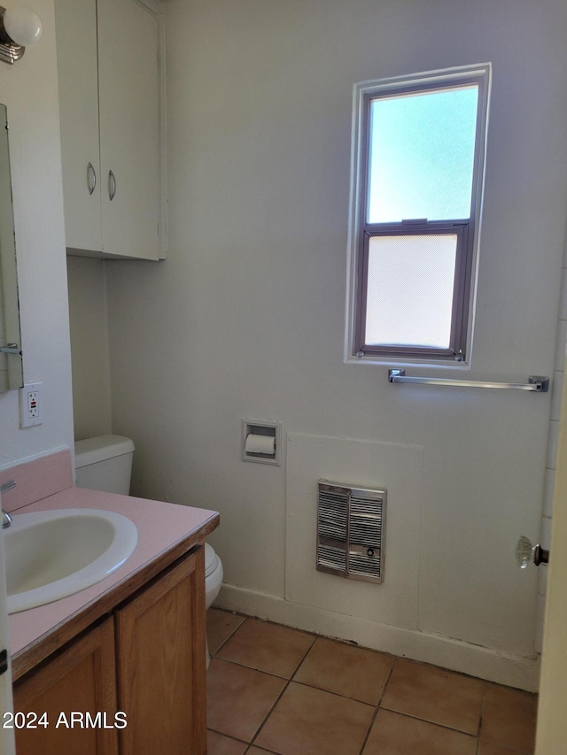 bathroom featuring toilet, heating unit, vanity, and tile patterned flooring