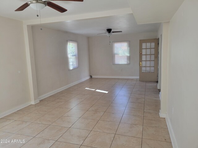 tiled empty room with ceiling fan and plenty of natural light