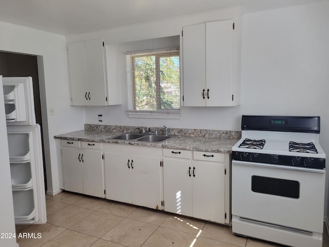 kitchen featuring white cabinets, light tile patterned floors, sink, and white stove