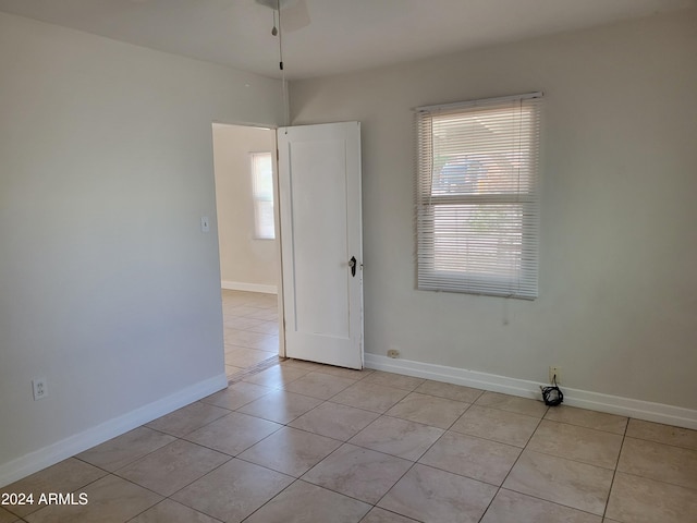 empty room with light tile patterned floors, ceiling fan, and plenty of natural light