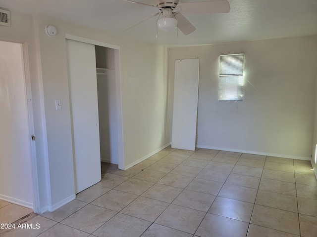 unfurnished bedroom with light tile patterned floors, ceiling fan, and a closet
