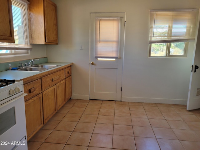 kitchen featuring a wealth of natural light, sink, gas range gas stove, and light tile patterned floors