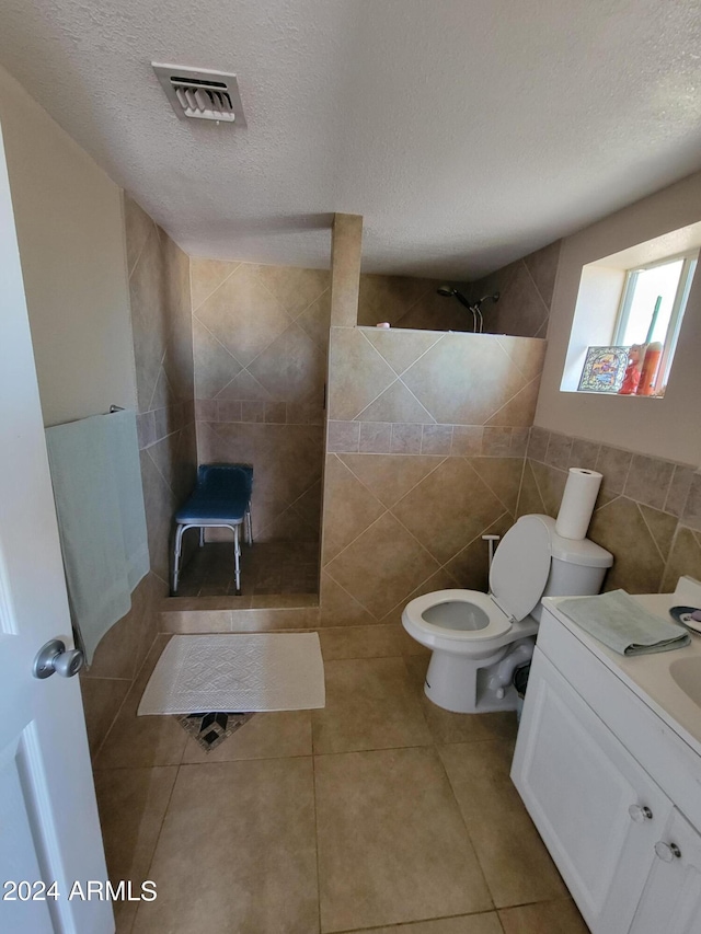 bathroom featuring vanity, tile walls, tile patterned floors, and a textured ceiling