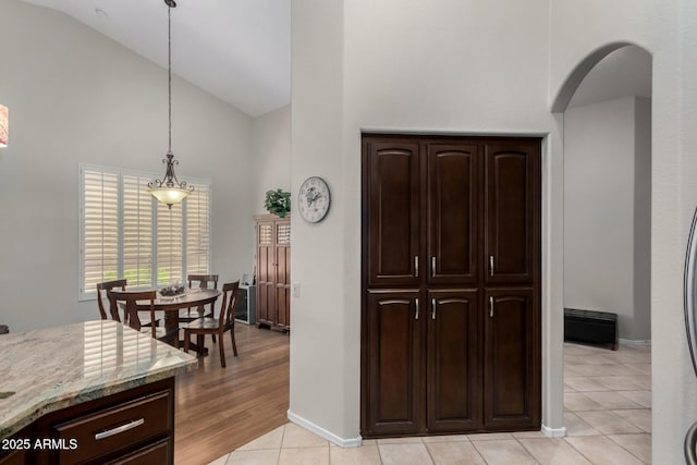 23813 S Pleasant Way, Sun Lakes, AZ 85248 - kitchen featuring dark brown cabinets, light tile patterned floors, high vaulted ceiling, baseboards, and light stone counters