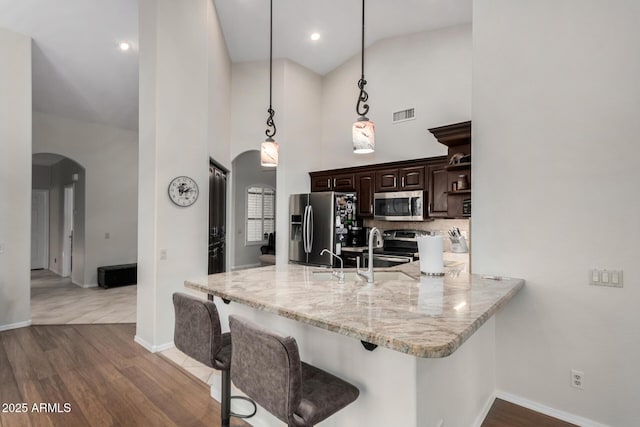 23813 S Pleasant Way, Sun Lakes, AZ 85248 - kitchen with dark brown cabinets, appliances with stainless steel finishes, a breakfast bar, arched walkways, and a towering ceiling