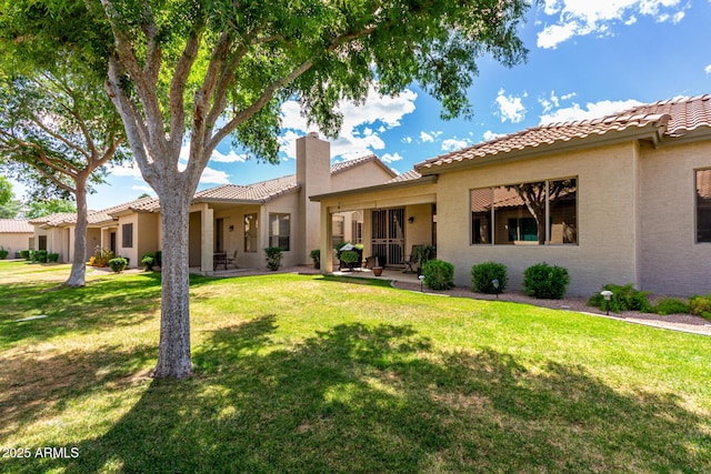 23813 S Pleasant Way, Sun Lakes, AZ 85248 - back of house with a tiled roof, a lawn, a chimney, and stucco siding