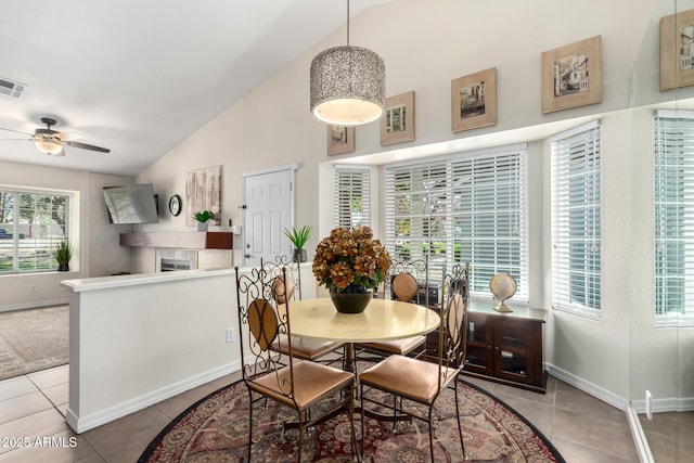 dining room featuring light tile patterned flooring, ceiling fan, lofted ceiling, and a tiled fireplace