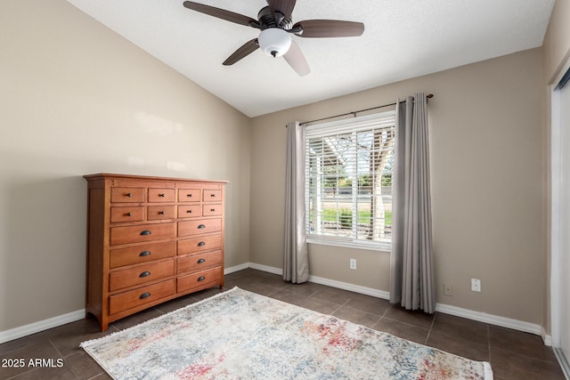 unfurnished bedroom featuring lofted ceiling, dark tile patterned flooring, and ceiling fan