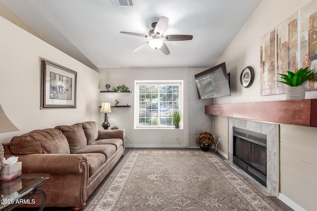 living room featuring a tile fireplace and ceiling fan