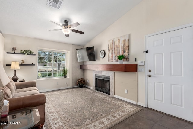 living room with dark tile patterned floors, vaulted ceiling, ceiling fan, and a fireplace