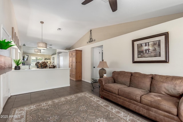 living room featuring ceiling fan, lofted ceiling, and dark tile patterned flooring