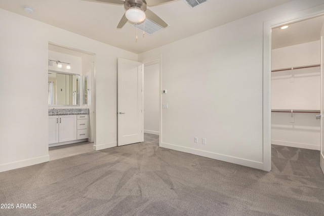 unfurnished bedroom featuring a walk in closet, ceiling fan, connected bathroom, light colored carpet, and a closet