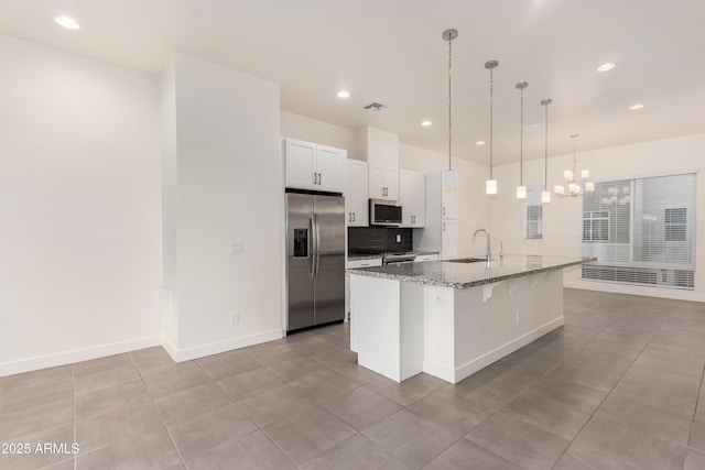 kitchen featuring stainless steel appliances, a kitchen island with sink, pendant lighting, stone countertops, and white cabinets