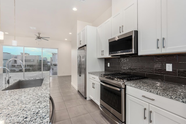 kitchen with white cabinetry, sink, light stone countertops, light tile patterned floors, and appliances with stainless steel finishes