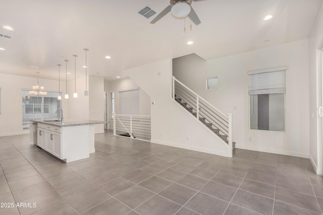 unfurnished living room with sink, ceiling fan with notable chandelier, and tile patterned flooring