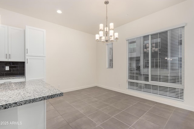 unfurnished dining area featuring tile patterned floors and a chandelier