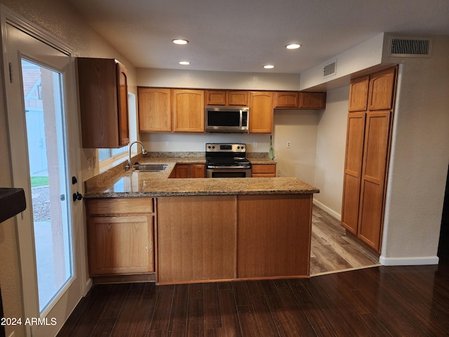 kitchen with stainless steel appliances, dark hardwood / wood-style flooring, sink, kitchen peninsula, and stone countertops