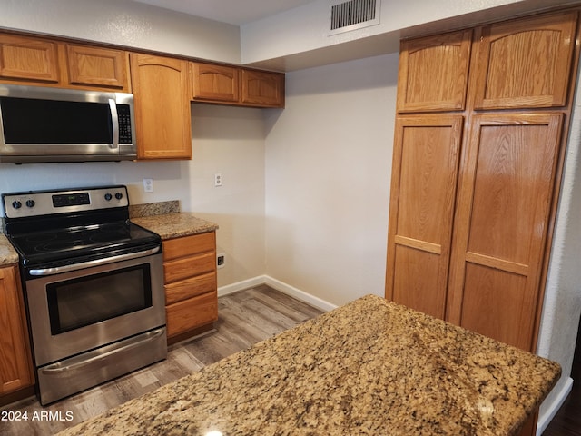 kitchen with light hardwood / wood-style flooring, light stone counters, and stainless steel appliances