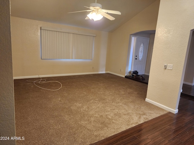 empty room featuring ceiling fan, dark colored carpet, and vaulted ceiling