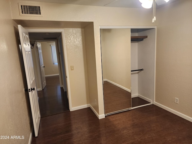 unfurnished bedroom featuring a closet and dark wood-type flooring