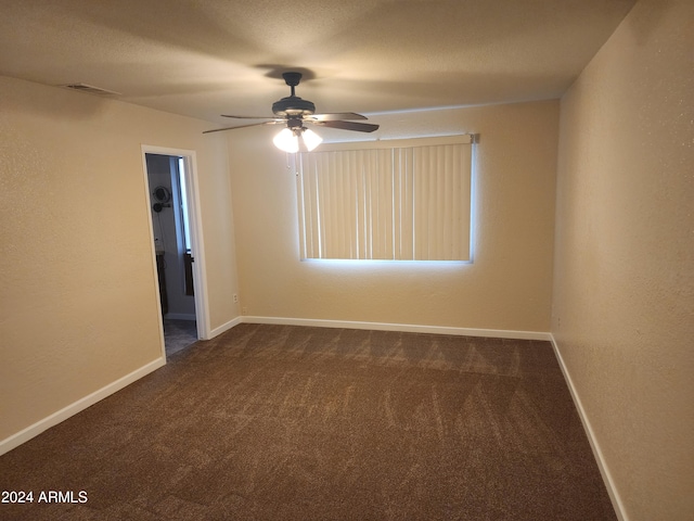 empty room with ceiling fan and dark colored carpet