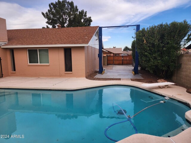 view of swimming pool featuring a patio area and a diving board