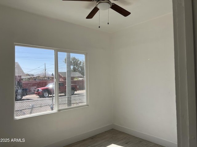 spare room with baseboards and wood finished floors