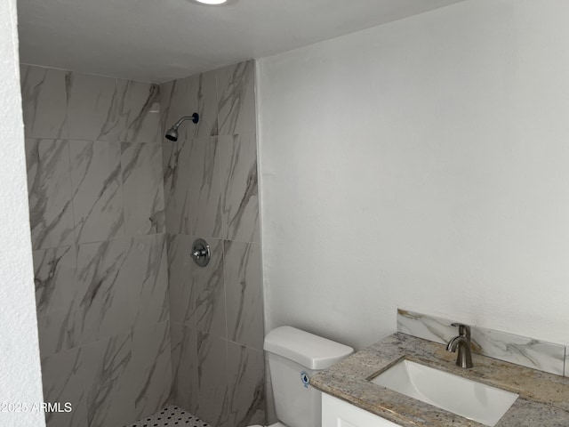 bathroom with vanity, a tile shower, and toilet