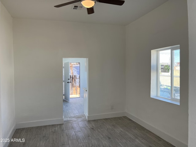 spare room with ceiling fan, wood finished floors, visible vents, and baseboards