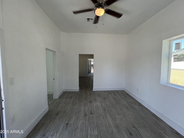 empty room featuring dark wood-style floors, ceiling fan, visible vents, and baseboards