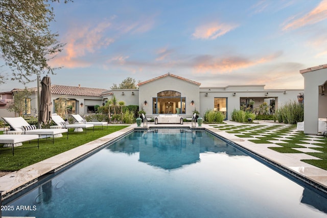 back house at dusk with an outdoor hangout area, a yard, and a patio area