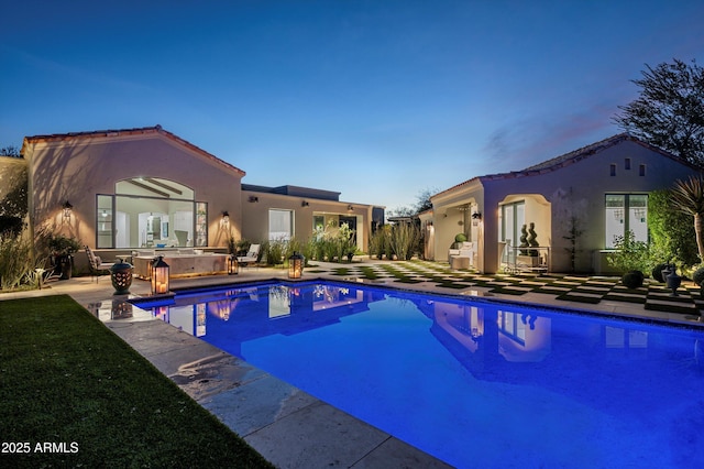 pool at dusk with a patio area