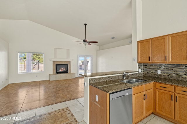 kitchen featuring light tile patterned floors, open floor plan, a peninsula, stainless steel dishwasher, and a sink