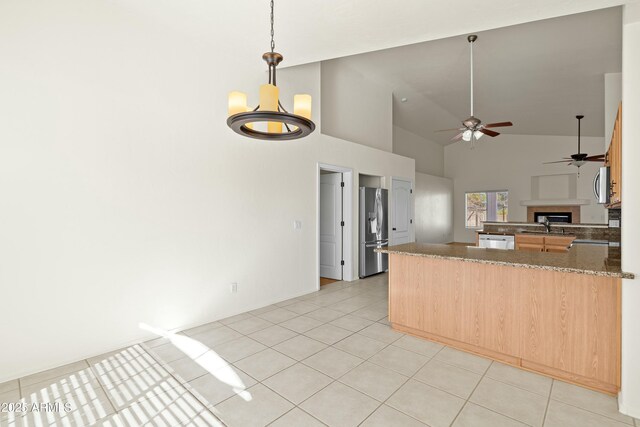 kitchen featuring light tile patterned floors, a fireplace, open floor plan, hanging light fixtures, and appliances with stainless steel finishes