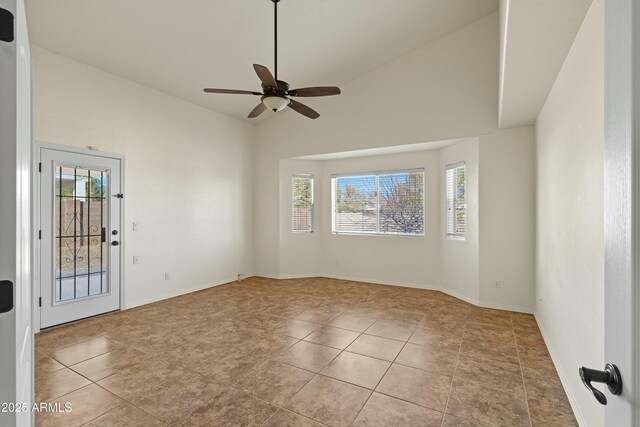 unfurnished room featuring a ceiling fan, lofted ceiling, baseboards, and light tile patterned floors