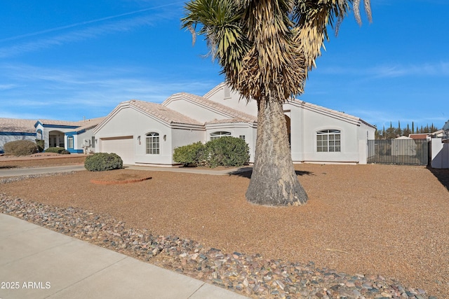 view of front of property with a garage, a tile roof, fence, and stucco siding